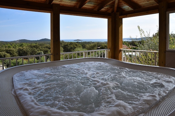 A hot tub with a view of the sea and hills.