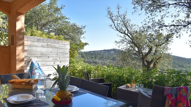An outdoor dining area with a table set for two, surrounded by wicker chairs, overlooking a scenic view of hills and trees. - Villa 2 Chambres (4 - 6 Personnes) (Sainte-Lucie de Porto-Vecchio)