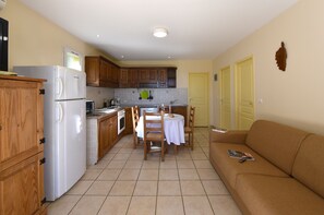 A compact kitchen with wooden cabinets, a white refrigerator, and a dining area with a table and chairs.