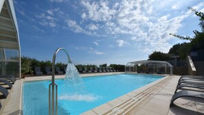 A swimming pool with a water fountain, lounge chairs, and a covered seating area. - Villa 2 Chambres (4 - 6 Personnes) (Sainte-Lucie de Porto-Vecchio)