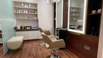 Un moderno salón de belleza con tres sillas, un espejo, estantes con productos para el cabello y piso de madera.
