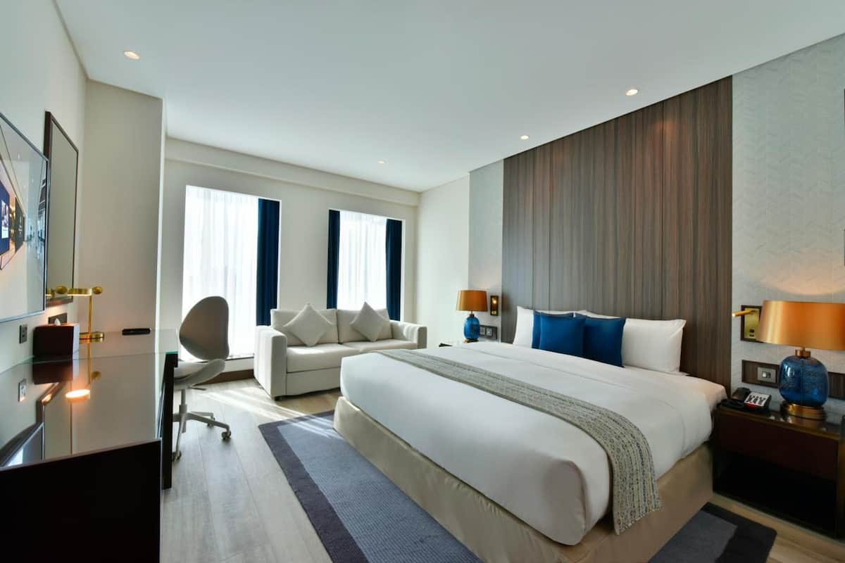 Una camera d'hotel moderna con un letto grande, una scrivania, una sedia e un divano.