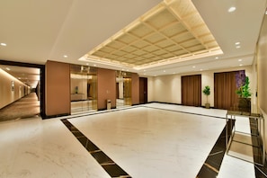 Enter a stylish lobby with a high ceiling and geometric pattern, featuring a reception area and comfortable seating.