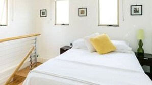 A hotel room with a large bed, a wooden staircase, and two windows.