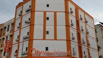 A multi-story hotel with a prominent orange and white facade, multiple balconies, and air conditioning units.