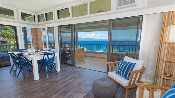 A spacious room with a dining area, a seating area with a view of the ocean, and a balcony with a railing. - Ridge 1921-22: Rare 3BR Luxury Villa w/Ocean Views (Lahaina)