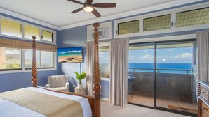 A bedroom with a four-poster bed, a ceiling fan, a view of the ocean through a sliding glass door, and a painting on the wall. - Ridge 1921-22: Rare 3BR Luxury Villa w/Ocean Views (Lahaina)