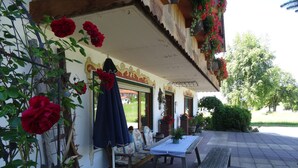An outdoor seating area with a table and benches, surrounded by potted plants and flowers. - Apartment Cornelia for 4 persons, 2 bedrooms, kitchenette, bathroom, 86 sqm (Inzell)