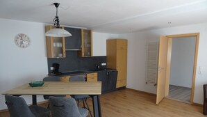 A modern kitchen with wooden cabinets, a dining table with chairs, and a clock on the wall. - Apartment Cornelia for 4 persons, 2 bedrooms, kitchenette, bathroom, 86 sqm (Inzell)