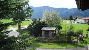 A rural setting with a small wooden structure, a fenced area, and a road leading to a building with a red roof. - Apartment Cornelia for 4 persons, 2 bedrooms, kitchenette, bathroom, 86 sqm (Inzell)