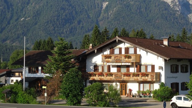 A traditional Alpine-style building with a balcony, surrounded by lush greenery and mountains in the background. - Apartment Cornelia for 4 persons, 2 bedrooms, kitchenette, bathroom, 86 sqm (Inzell)