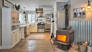 Una cocina con armarios blancos, una isla central, estufa y una lámpara colgante.
