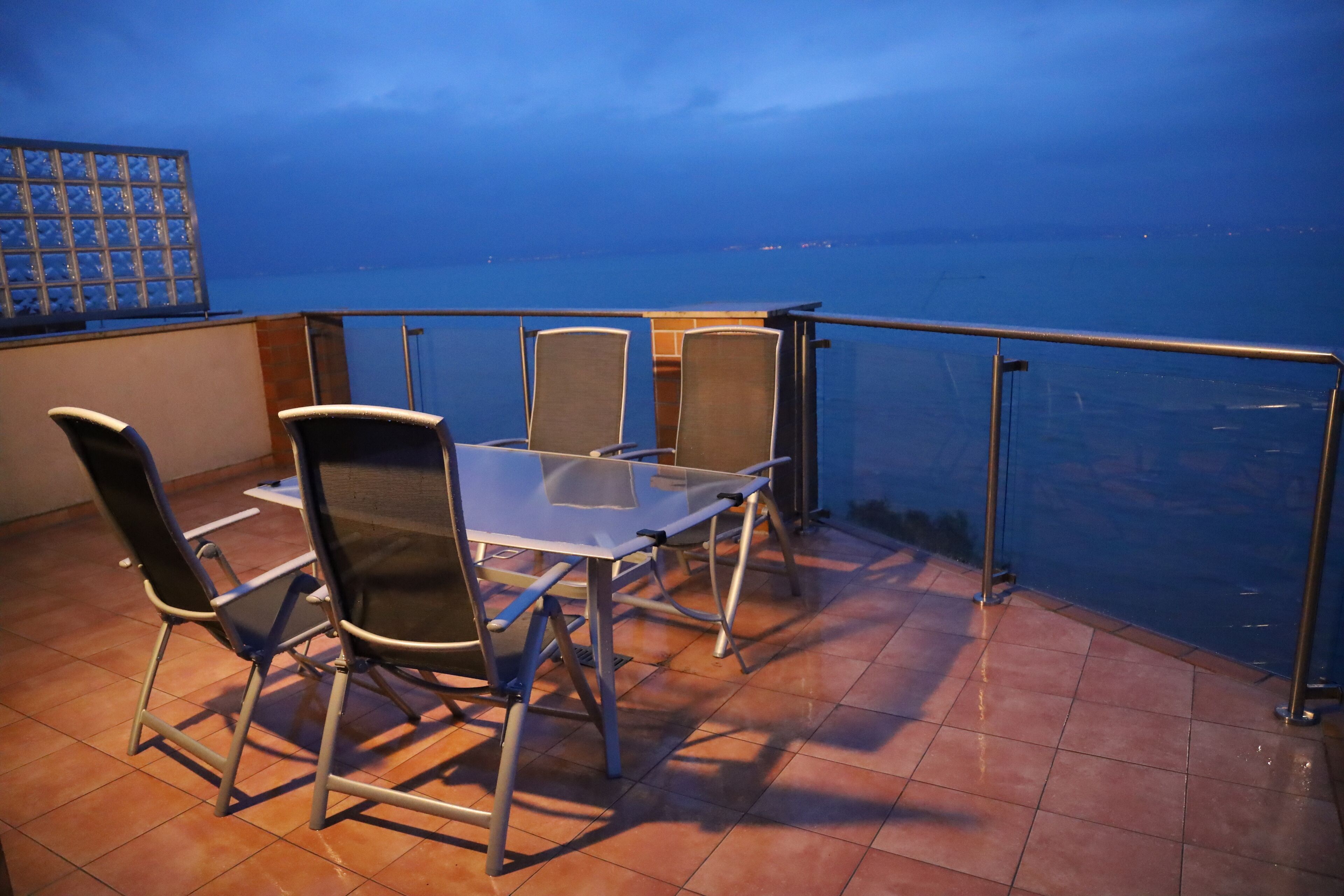 Une terrasse avec une table et des chaises, donnant sur une étendue d’eau.