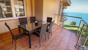 A balcony with a table and chairs, overlooking a body of water and buildings.