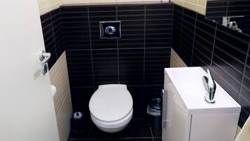 Une petite salle de bain avec des toilettes, un lavabo et un miroir.