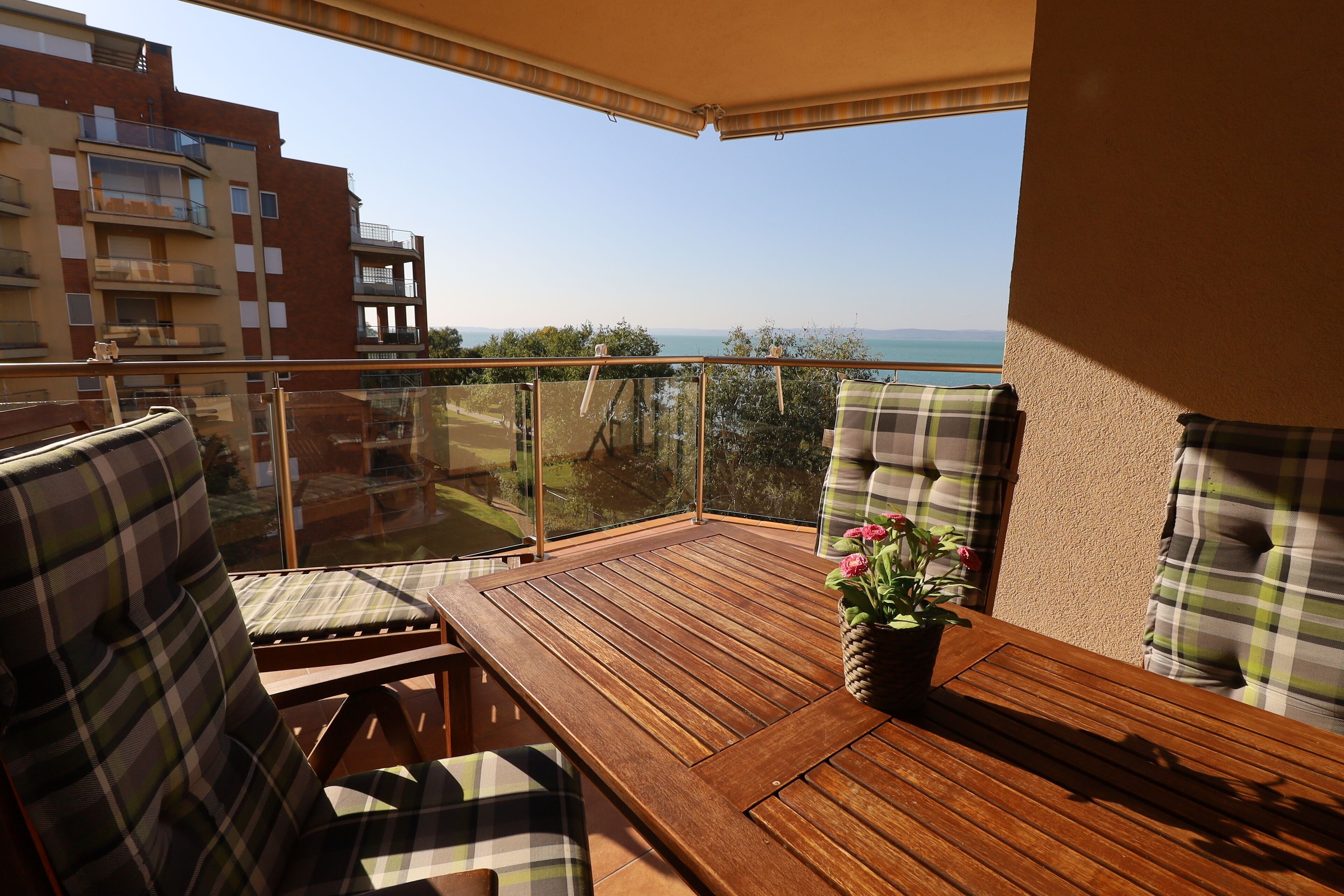 Un balcone con mobili in legno, una pianta in vaso e vista sul mare.