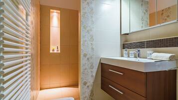 Ein Badezimmer mit Dusche, Waschtisch mit Spiegel und Handtuchhalter.
