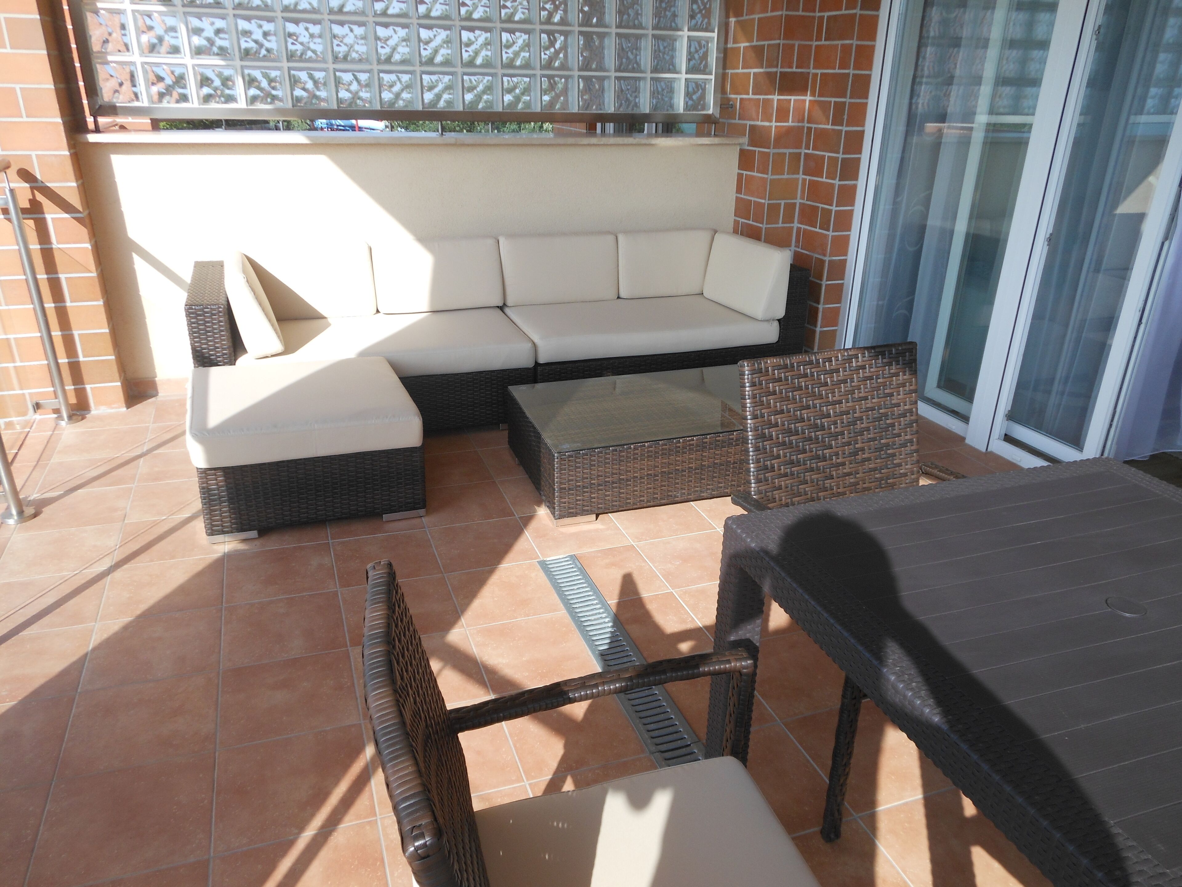 Un espace extérieur aménagé avec un canapé, des fauteuils en osier et une table.