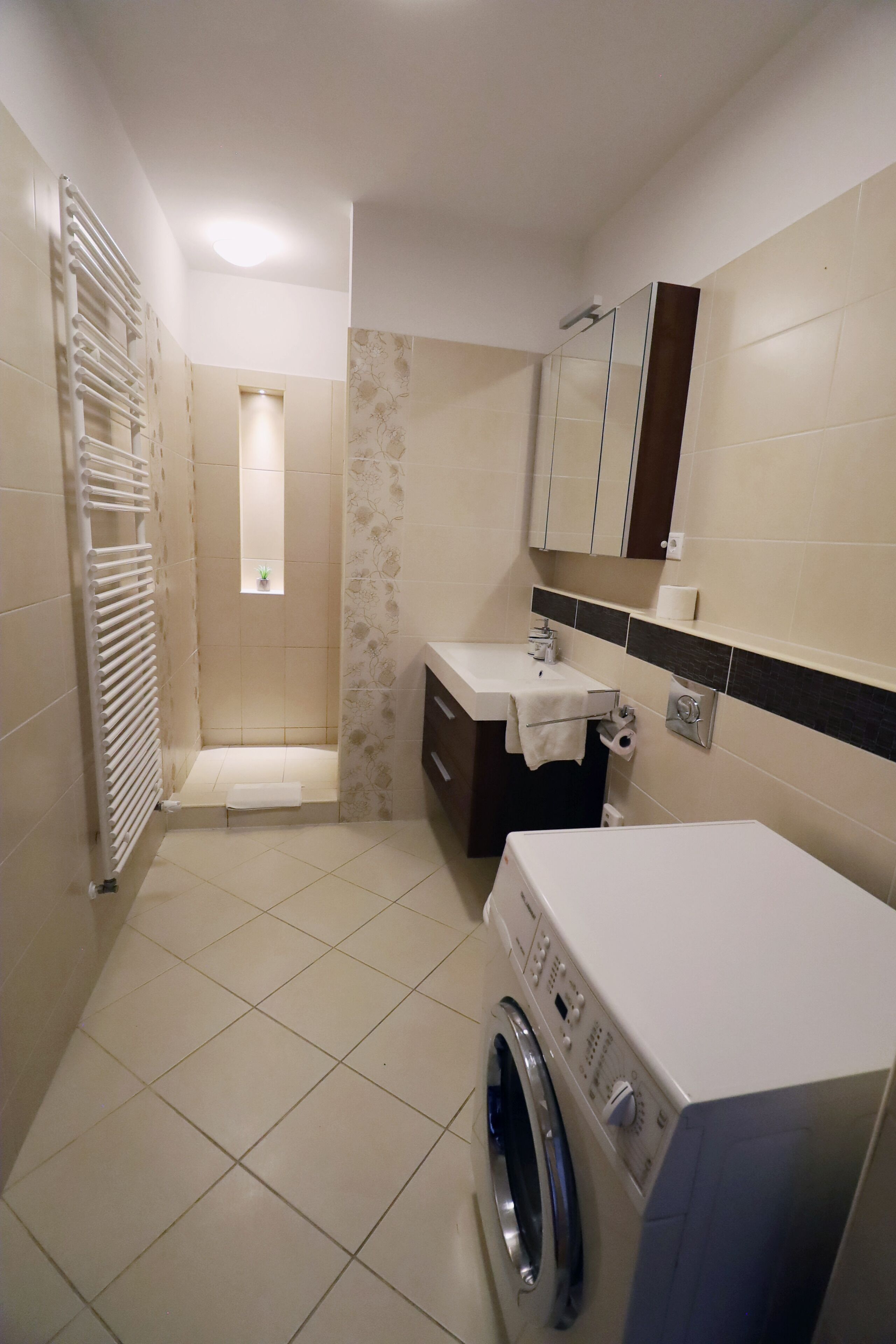 Casa de banho compacta com chuveiro, sanita e máquina de lavar roupa.