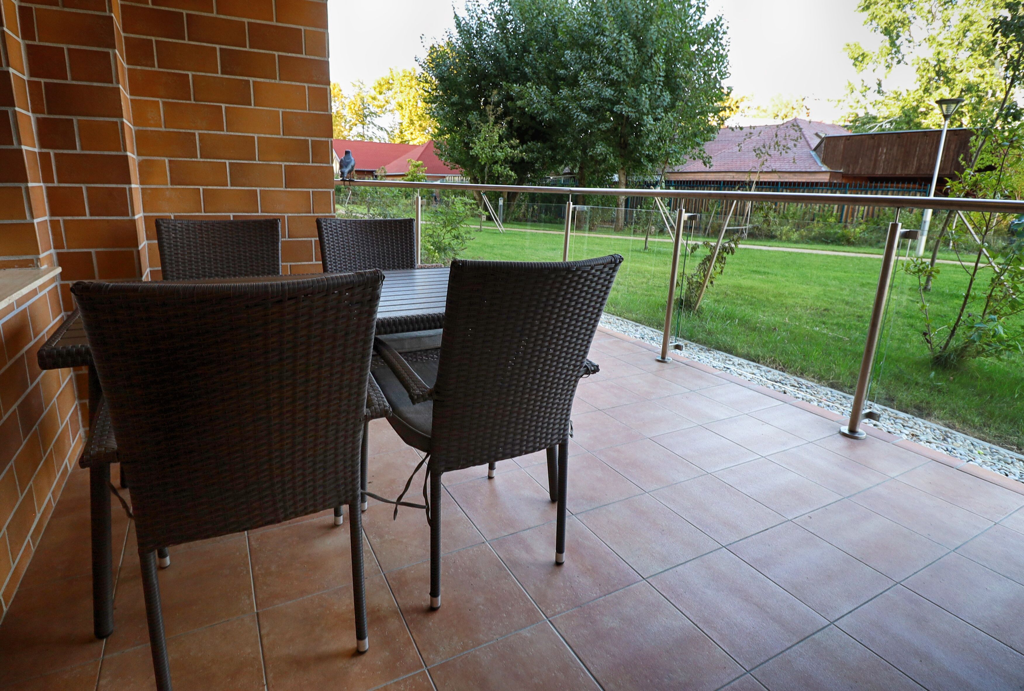 An outdoor patio with wicker furniture and a view of a grassy yard.