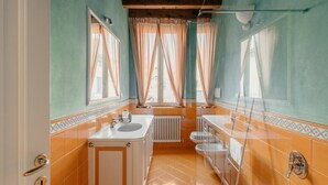 Un baño con una ventana grande, un lavabo, un inodoro y una bañera.