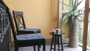 Une pièce avec deux chaises noires, une petite table ronde sur laquelle se trouvent une tasse et une soucoupe, et une plante en pot.