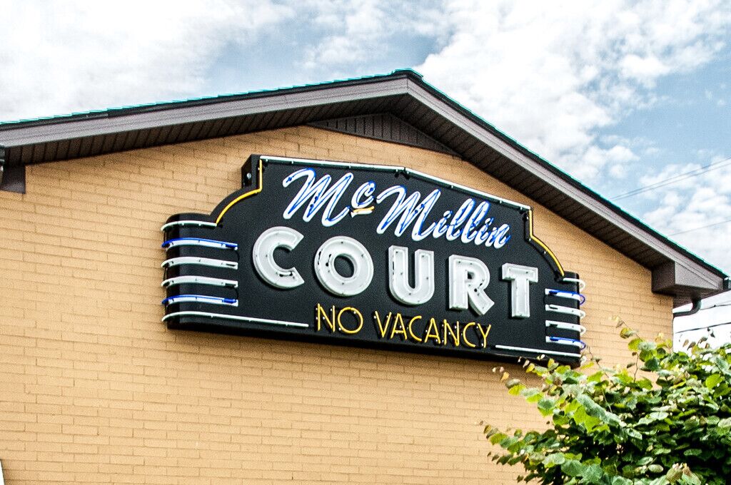 Ein Schild für McMillin Court mit dem Text 'KEINE FREIEN ZIMMER' an einem Backsteingebäude.