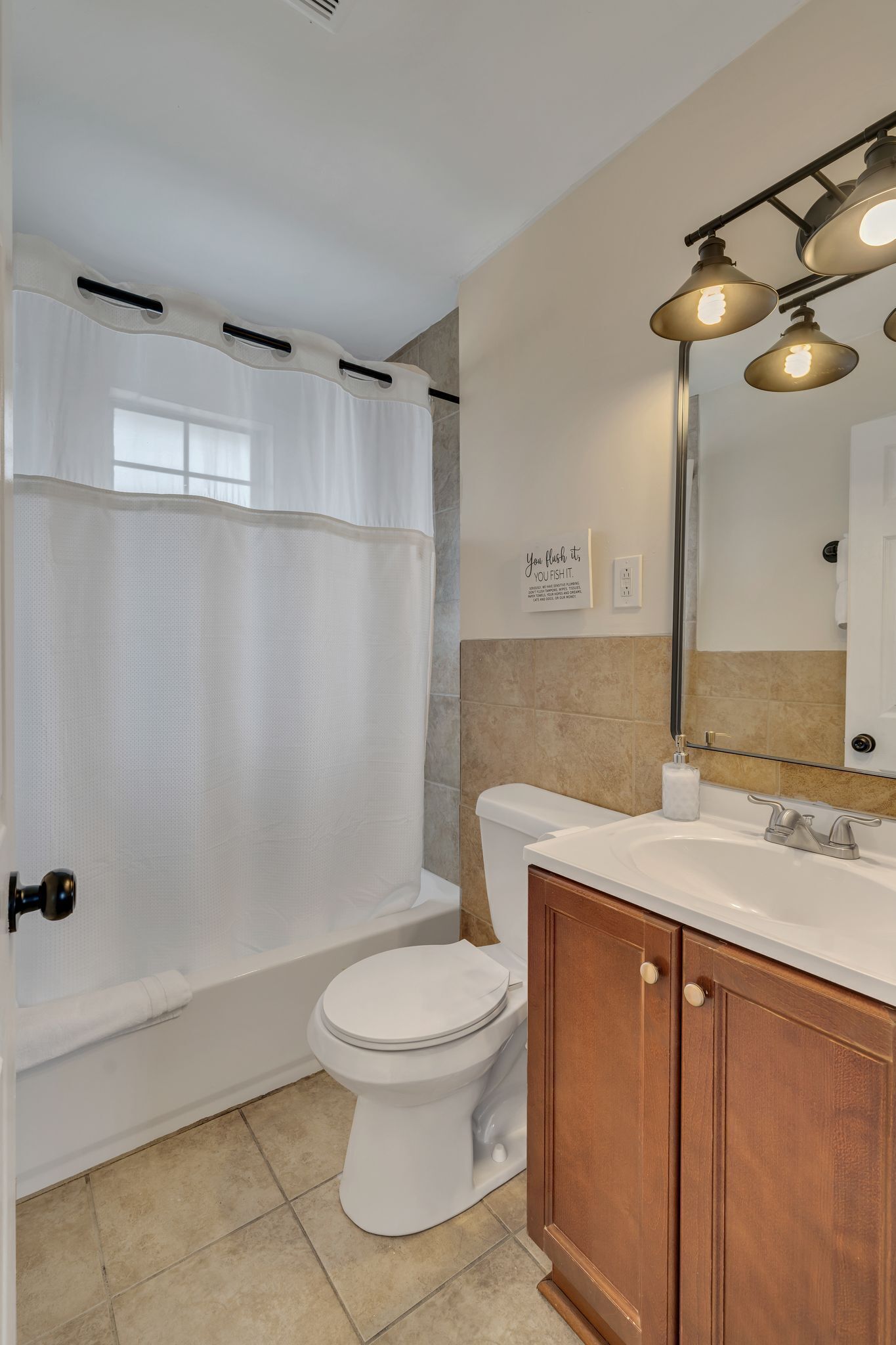 A bathroom with a bathtub, toilet, and vanity with a mirror.