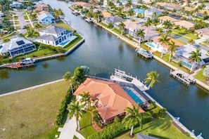A residential area with a large house featuring a swimming pool, a dock, and a canal.