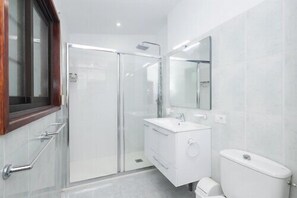 Ein modernes Badezimmer mit einer Duschkabine aus Glas, einem weißen Waschbecken und einer Toilette.