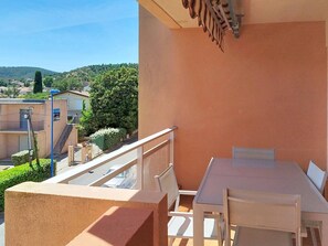 Ein Balkon mit Tisch und Stühlen, mit Blick auf eine Wohngegend mit Häusern und Bäumen.