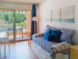 A room with a bed, a table, chairs, a lamp, and a view through a glass door.