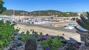 A marina with boats, a clear sky, and a hilly landscape in the background.