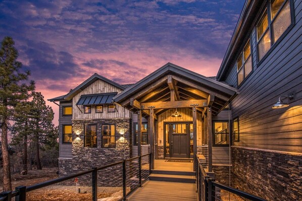 A two-story house with a stone facade, a wooden deck, and a covered porch.