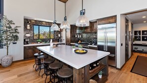 Una cocina moderna con una isla grande, taburetes de bar y vistas al exterior.