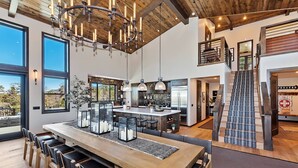 A spacious kitchen with a large island, bar area, and a staircase leading to a loft.