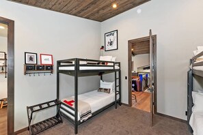 Habitación con literas, techo de madera, un cuadro en la pared y un banco.