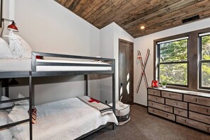 Habitación con literas, una cómoda y esquíes apoyados en la pared.