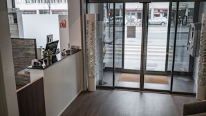 A hotel reception area with a desk, a chair, and a large glass door leading to the street. - Starling Hotel Residence Genève (Geneva)