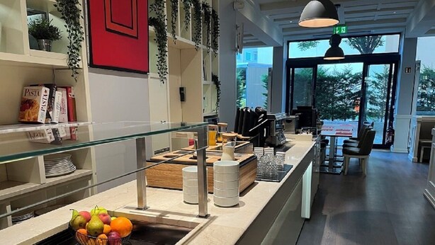 A buffet area with a variety of fruits and vegetables, a pasta section, and a seating area with tables and chairs. - Starling Hotel Residence Genève (Geneva)