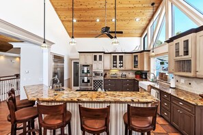 Una cocina moderna con una isla central, taburetes de bar y un ventilador de techo.