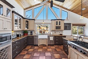 A kitchen with a large window, a stove, and a dishwasher.