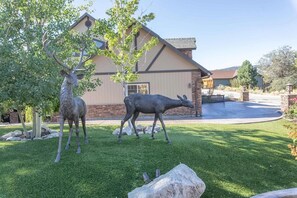 A house with a stone facade, a lawn, and two deer statues.