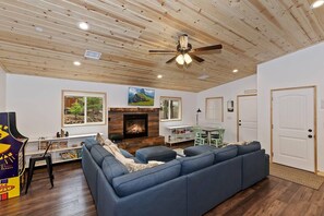 A living room with a fireplace, a ceiling fan, and a large blue sofa.