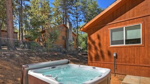 A wooden cabin with a hot tub in front.