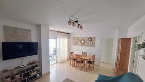 Un salon équipé d’un téléviseur, de meubles en bois et d’un coin repas avec une table et des chaises.