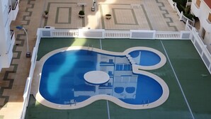 Une piscine au design original, entourée d’une clôture blanche et agrémentée de plantes en pot.