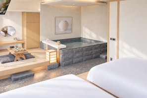 Una habitación de hotel moderna con zona de spa, que incluye una bañera y una pequeña mesa con juego de té.