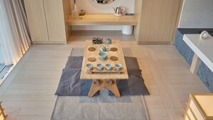 A wooden table with bowls and a teapot, set on a woven mat in a room with wooden flooring and a bench in the background. - UH Suite The Seoul (Seoul)