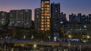 A high-rise building with multiple floors, a prominent entrance, and a well-lit facade. - UH Suite The Seoul (Seoul)